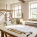 Chantier de rénovation d’une maison angevine lumineux et ordonné, avec des plans ouverts sur une table de travail, des outils et des matériaux soigneusement rangés.