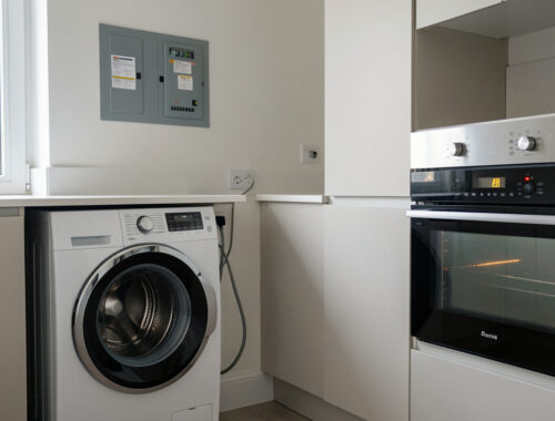 Un lave-linge et un four électriques près d’un tableau électrique domestique dont le disjoncteur est déclenché.