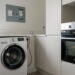 Un lave-linge et un four électriques près d’un tableau électrique domestique dont le disjoncteur est déclenché.